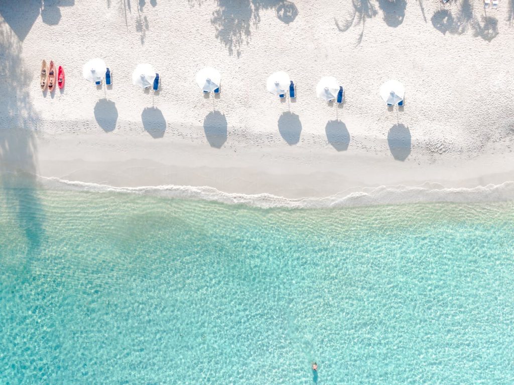 Aerial shot of a serene beach with umbrellas and turquoise water perfect for relaxation.